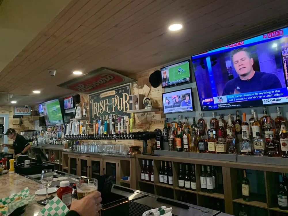 The bar at The Irish Goodbye Pinthouse with the Irish Pub sign, taps and TVs