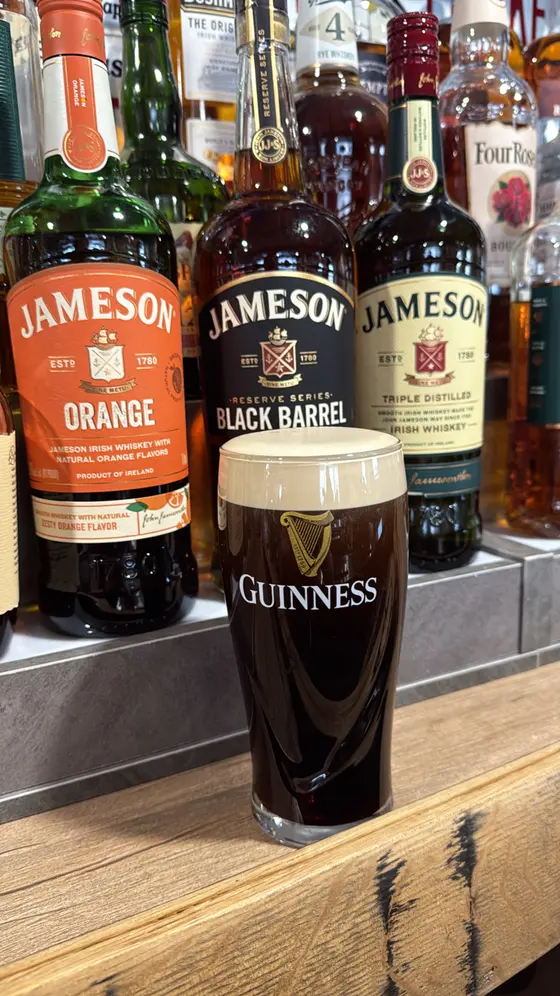 A pint of Guinness in front of Jameson bottles