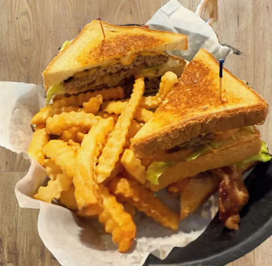 Grilled sandwich stacked on crinkle cut fries