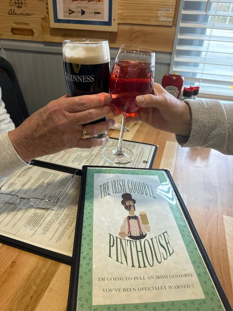 Two guests clinking glasses over The Irish Goodbye Pinthouse menu
